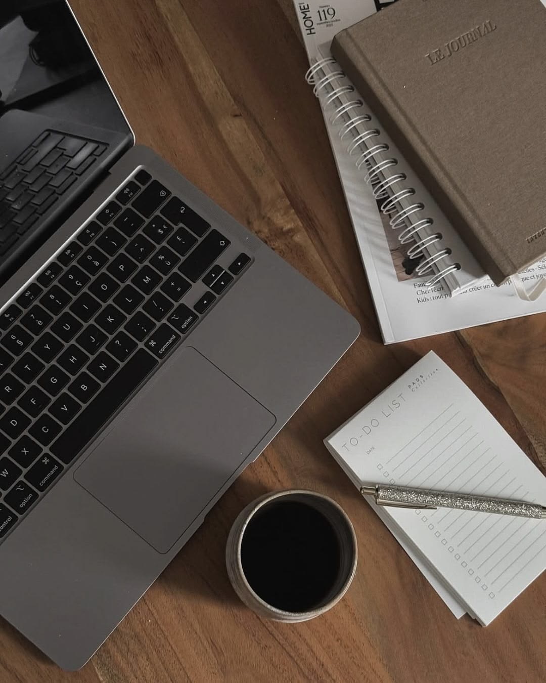 Portátil, cuaderno y café en una mesa de madera, vista desde arriba