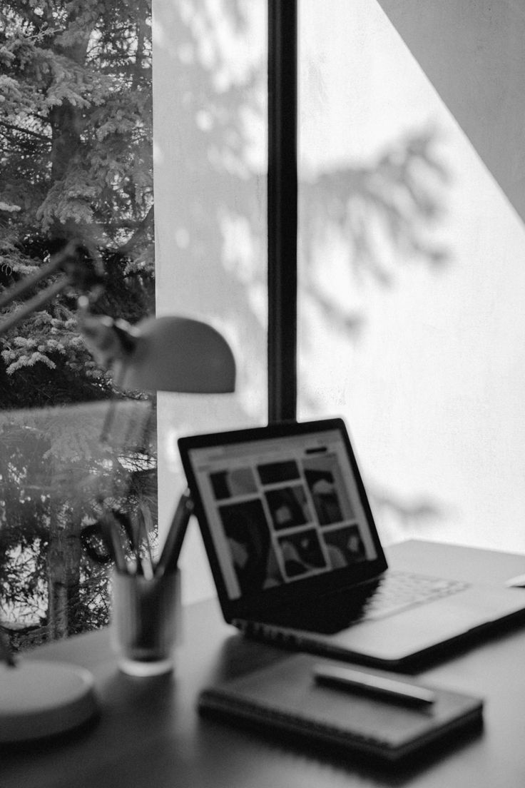 Laptop on a desk by a window, quiet working light