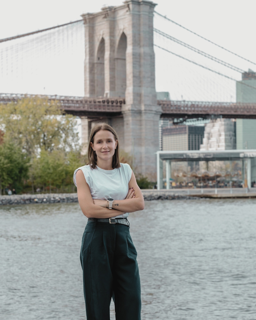 Niko standing by the East River, Brooklyn Bridge behind