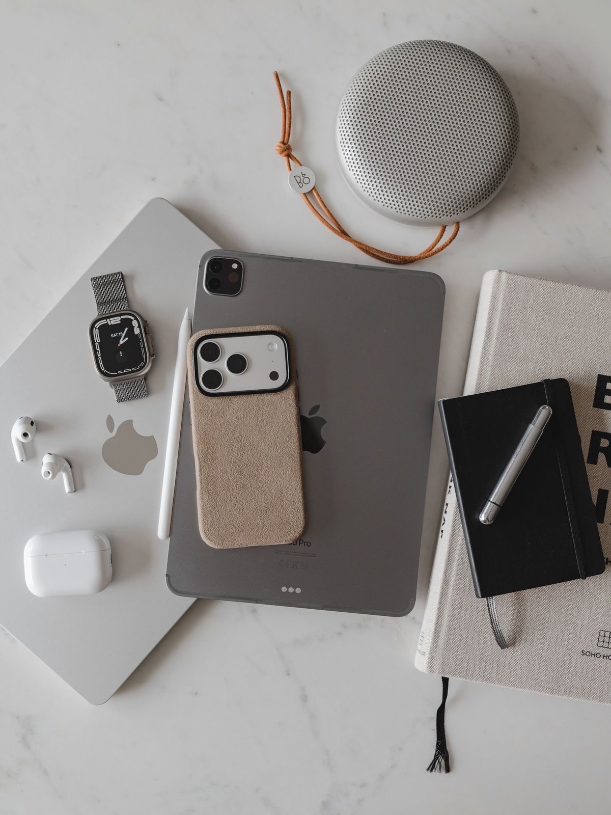 Composición de un teléfono, tablet, smartwatch y cuadernos sobre una superficie de mármol