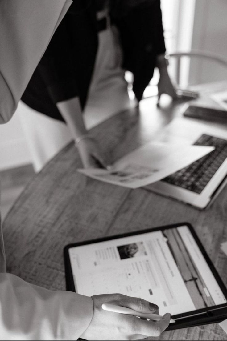 Revisando páginas impresas y una tablet en una mesa de reuniones, en blanco y negro